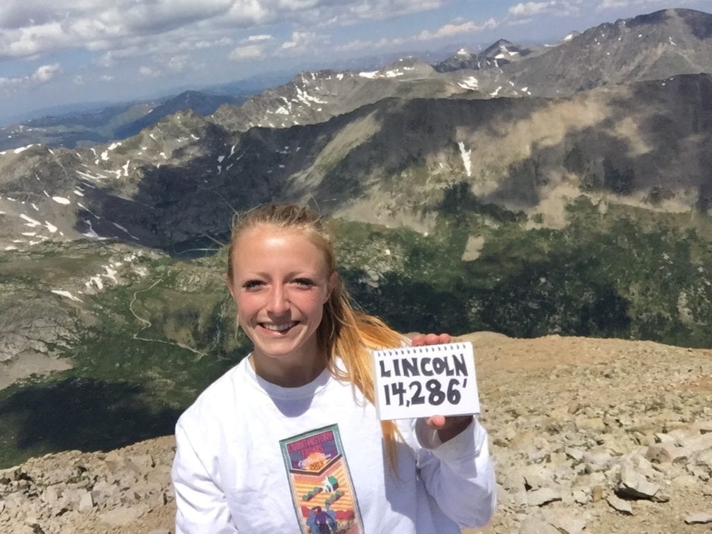 A view from the top of Mount Lincoln as Laura holds up her summit victory sign.