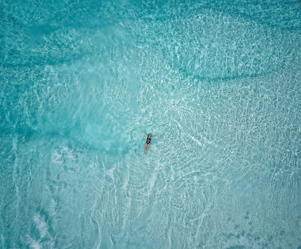 Drone picture of Laura swimming in the turquoise waters of Lucky Bay